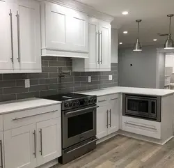 Photo of white kitchen with gray appliances