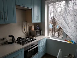 Kitchen design with a refrigerator by the window and a gas stove