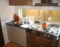 Газовая плита у окна в интерьере кухни