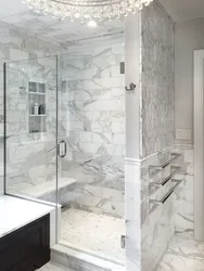Мрамордан жасалған душ пен дәретханасы бар ванна бөлмесінің дизайны