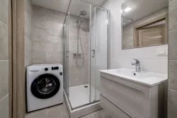 Photo of a bathroom with a shower and a washing machine without a toilet