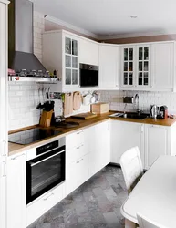 Белая кухня с деревянной столешницей и черными ручками в интерьере