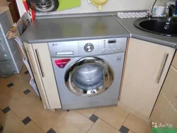 In the kitchen there is a washing machine and dishwasher photo