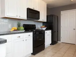 Black refrigerator in a white kitchen in the interior photo