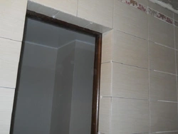 Есіктің жанындағы ванна бөлмесінің плиткаларының суреті