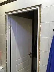 Есіктің жанындағы ванна бөлмесінің плиткаларының суреті