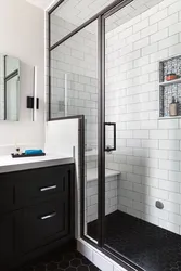 Black shower cabin in the interior of a white bath