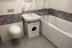 Vertical washing machine in the bathroom interior