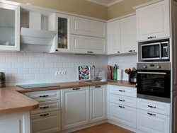 Photo of a white kitchen with wooden walls