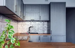 Серая кухня с деревянной столешницей и фартуком под дерево фото