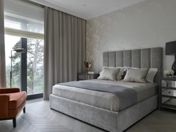 Gray bed with a soft headboard in the bedroom interior photo
