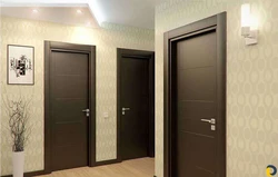 Dark floor and light doors in the interior photo of the apartment