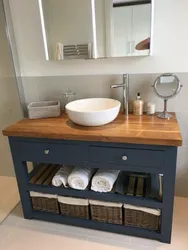Photo of a bathtub with a sink and a bedside table in the bathroom