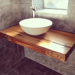 Photo of a bathtub with a sink and a bedside table in the bathroom