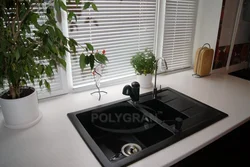 Photo of a kitchen with a white countertop and a black sink