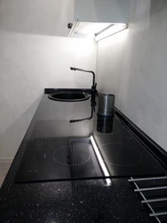 Photo of a kitchen with a white countertop and a black sink