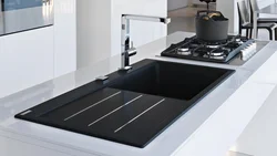 Photo of a kitchen with a white countertop and a black sink