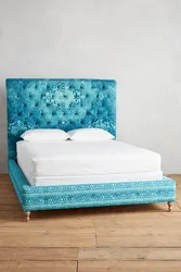 Turquoise bed in a bedroom interior with a soft headboard