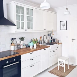 Ошхона сафед бо countertop чӯбӣ ва дастаки сиёҳ дар дохили