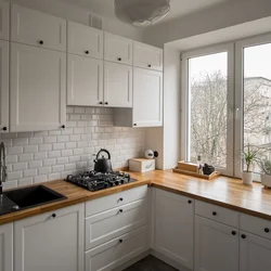 White kitchen with wooden countertop and black handles in the interior