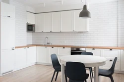 Ошхона сафед бо countertop чӯбӣ ва дастаки сиёҳ дар дохили