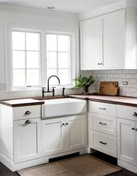 White Kitchen With Wooden Countertop And Black Handles In The Interior