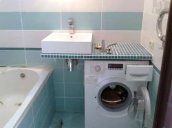 Bathroom design with a sink above the washing machine photo
