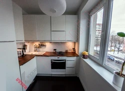 Corner kitchen design photo with refrigerator by the window