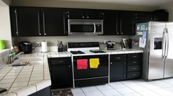 Photo of a kitchen with a black countertop and a black refrigerator